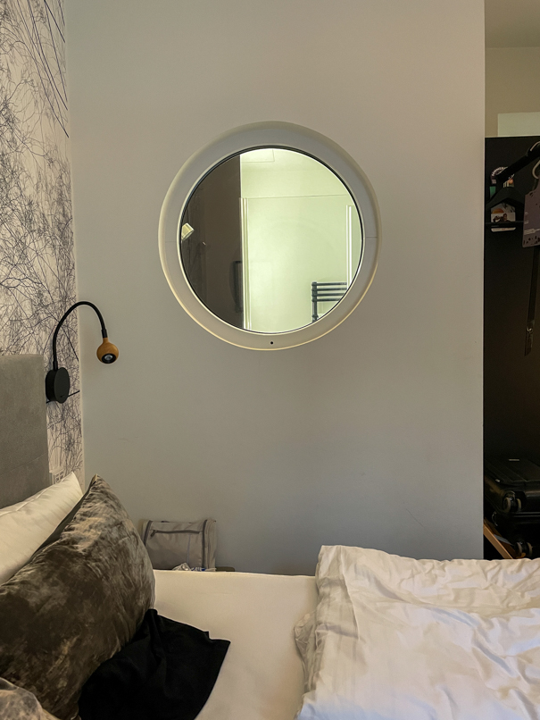 Blick auf das Bett mit Fenster zum Badezimmer im Boutique Hotel K7.